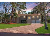 Charming home featuring a brick driveway, lush lawn, and mature trees at 1130 Serpentine S Dr, St Petersburg, FL 33705