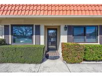 Inviting front entrance with a red tiled roof, lush green landscaping, and a modern glass door at 19029 Us Highway 19 N # 17A, Clearwater, FL 33764