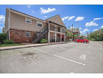 Apartment building with brick facade, balconies, and parking spots on a sunny day at 200 Country Club Dr # 1001, Largo, FL 33771