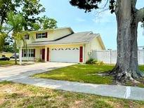 Charming home featuring a two-car garage, well-maintained lawn, and mature trees, creating a welcoming curb appeal at 2510 Cypress Bend E Dr, Clearwater, FL 33761