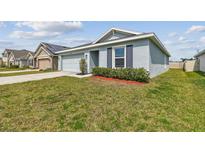 Charming single-story home with a well-manicured lawn, blue painted exterior, and neat landscaping at 8034 Broad Pointe Dr, Zephyrhills, FL 33540