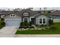 Charming one-story home featuring a manicured lawn, stone-lined garden beds, and a two-car garage at 12704 Palapa Loop, Spring Hill, FL 34610