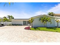 Charming one-story home with lush landscaping, palm trees, and a brick driveway on a sunny day at 3102 W Vina Del Mar Blvd, St Pete Beach, FL 33706
