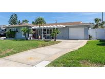 Charming single-story home featuring a well-manicured lawn, attached garage, and a welcoming covered entryway at 553 E Lake Dr, Largo, FL 33771