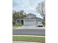Charming home with a three car garage, lush landscaping, and a welcoming front porch at 9729 Asbel Estates St, Land O Lakes, FL 34638