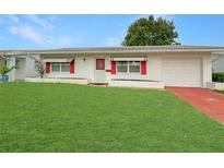 Charming single-story home featuring a well-manicured lawn, attached garage, and red window awnings at 9737 36Th N Way, Pinellas Park, FL 33782