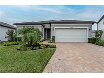 Charming single-story home featuring a well-manicured lawn, brick driveway, and a two-car garage at 10812 Applewood Range Way, Tampa, FL 33647