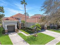 Beautiful two-story home featuring a lush green lawn, tropical landscaping, and a tile roof at 11620 Bristol Chase Dr, Tampa, FL 33626