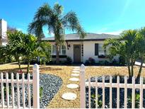 Charming single-story home with a well-manicured front yard and white picket fence at 14066 Marguerite Dr, Madeira Beach, FL 33708