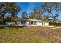 Charming single story home featuring a front lawn, driveway, and white fence, surrounded by mature trees at 2050 Nigels Dr, Dunedin, FL 34698