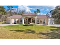 Stunning single-story home featuring manicured lawn, central fountain, a light stucco facade, and a symmetrical design at 22259 Skyview Cir, Brooksville, FL 34602