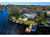Waterfront home featuring a private pool, boat dock, and lush tropical landscaping with views of the city skyline at 3399 Maple Ne St, St Petersburg, FL 33704