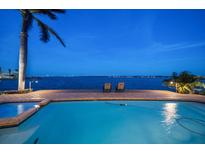 Inviting waterfront pool with two lounge chairs on the brick-paved pool deck under the light of early evening at 447 22Nd St, Belleair Beach, FL 33786