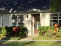 Charming townhome front entrance with a well-manicured lawn, shrubs, and exterior window treatments at 860 Glen More Ct # B, Palm Harbor, FL 34684