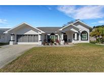 Charming single-story home with a well-manicured lawn, neutral color palette, and inviting entrance at 14247 Spanish Wells Dr, Hudson, FL 34667