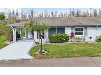 Charming single-story home with well-manicured lawn, mature palm tree, and covered parking area at 2022 Heathfield Cir, Sun City Center, FL 33573