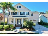 Charming two-story home featuring a manicured front yard, a covered porch, blue shutters, and an attached two-car garage at 310 Manns Harbor Dr, Apollo Beach, FL 33572