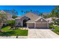 Beautiful home featuring a well-manicured lawn, palm trees, and a spacious three-car garage at 3537 Valencia Cove Court, Land O Lakes, FL 34639