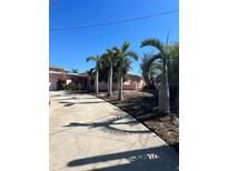 Charming single-story home with a vibrant pink exterior and a well-maintained front yard with mature palm trees at 3800 Belle Vista E Dr, St Pete Beach, FL 33706