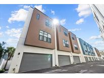 Modern townhome row featuring two-car garages, neutral exteriors and ample natural light against blue sky at 4810 W Mcelroy Ave # 7, Tampa, FL 33611