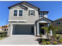 Two-story home with a two car garage, neat landscaping, and a brick paved driveway at 7105 119Th E Ct, Palmetto, FL 34221