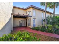 Inviting two-story condo featuring a private patio, red tile roof, and lush landscaping at 7200 Ulmerton Rd # B4, Largo, FL 33771
