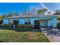 Charming single-story home with a well-manicured lawn, lush landscaping, and a brick driveway at 8450 Candlewood Rd, Seminole, FL 33777