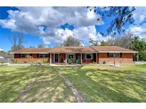 Charming brick home featuring a large front yard, cozy porch, and inviting curb appeal at 114 Laurel Tree Way, Brandon, FL 33511