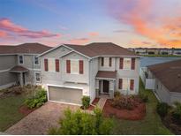Charming two-story home featuring a brick driveway, two-car garage, and manicured landscaping at sunset at 11544 Brighton Knoll Loop, Riverview, FL 33579