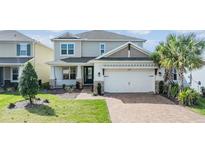 Charming two-story home featuring a well-manicured lawn and a brick-paved driveway leading to a two-car garage at 13676 Stansil Ave, Odessa, FL 33556