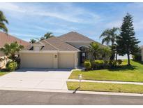 Charming home featuring a well-manicured lawn, a spacious three-car garage and beautiful landscaping at 1648 Mira Lago Cir, Ruskin, FL 33570