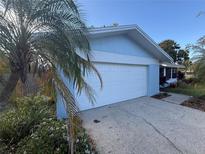Attached two-car garage in a light-blue home with mature landscaping and a white garage door at 1982 Seton Dr, Clearwater, FL 33763