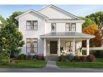 Charming two-story home with a covered front porch, manicured lawn, and beautifully landscaped flower beds at 2402 N Glenwood Dr, Tampa, FL 33602