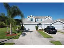 Two-story home featuring a light blue exterior, gray roof, blue shutters, and a spacious driveway with two cars parked at 284 Hemingway Dr, Oldsmar, FL 34677