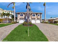 Beige home featuring dual garages, staircase, and tropical landscaping at 750 123Rd Ave, Treasure Island, FL 33706