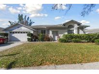 Charming single-story home with an attached two-car garage and well-manicured landscaping at 915 Brittany Park Blvd, Tarpon Springs, FL 34689