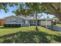 Charming single-story home featuring a manicured lawn, lush landscaping, and a carport for convenient parking at 9862 48Th N Ave, St Petersburg, FL 33708
