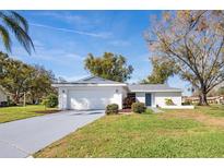 Charming single-story home featuring a well-manicured lawn, mature trees, and a two-car garage at 1022 Mctavish Way, Palm Harbor, FL 34684