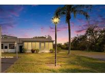 Charming home exterior featuring a well-manicured lawn, mature trees, and a cozy enclosed porch under a colorful sky at 206 Andover N Pl # 96, Sun City Center, FL 33573