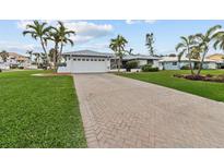 Charming single-story home with a manicured lawn, beautiful landscaping, and a brick paver driveway at 8000 13Th S Ave, St Petersburg, FL 33707