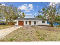 Charming single-story home with a fresh white exterior, a brown garage door, and a well-maintained front yard at 8930 94Th Ave, Seminole, FL 33777