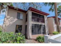 Exterior view of a two-story condo with a screened porch on the second story, surrounded by tropical landscaping at 8640 Tahoe Ct # 16, Tampa, FL 33614