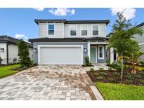 Charming two-story home showcasing a well-manicured lawn and a driveway paved with decorative brick at 10410 Cross River Trl, Parrish, FL 34219