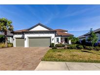 Charming home with a brick driveway, well-maintained lawn, mature palm trees and a three car garage at 11257 Egeria Dr, Odessa, FL 33556