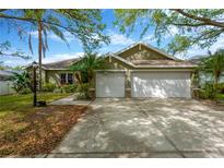 Charming home featuring a two-car garage, tidy landscaping, and mature trees in a residential neighborhood at 1166 Lumsden Trace Cir, Valrico, FL 33594