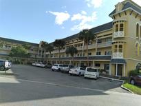 A multi-story yellow apartment building shows balconies, palm trees and parking on a sunny day at 2459 Franciscan Dr # 35, Clearwater, FL 33763