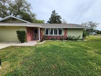 Charming single-story home with a brick accent, well-maintained lawn and landscaped flower beds at 113 Michigan Blvd, Dunedin, FL 34698