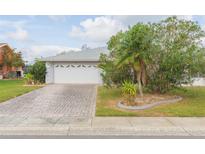 Charming home featuring a two-car garage, brick driveway, and lush landscaping at 1816 N Pebble Beach Blvd, Sun City Center, FL 33573