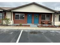 Cozy brick condo featuring a blue front door with a festive wreath and well-maintained landscaping at 24862 Us Highway 19 N # 1504, Clearwater, FL 33763