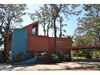 Unique home featuring a modern design, a cylindrical tower, and a convenient carport, all surrounded by mature trees at 7219 Williams S Dr, St Petersburg, FL 33705